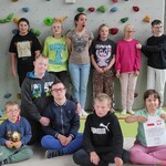 Uczestnicy półkolonii na tle ścianki wspinaczkowej