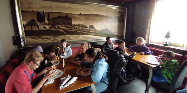 Uczestnicy półkolonii siedzą przy stołach w restauracji
