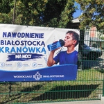 Plakat wiszący na płocie przed szkołą reklamujący picie wody z kranu