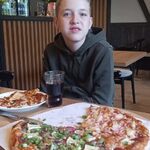 Solenizant siedzi przy stole na którym stoi pizza
