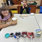 Uczennice siedzą przy stole, przed nimi leżą przygotowane produkty.