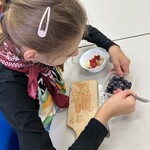 Uczennica nakłada owoce łyżką.