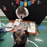 Uczennic wybiera pióro spośród piór leżących na stole