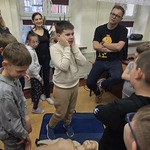 Uczniowie i prowadzący warsztaty stoją wokół fantomu leżącego na podłodze
