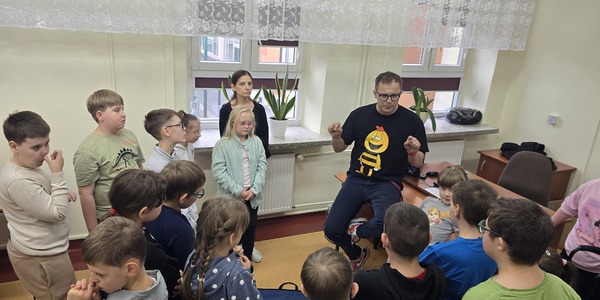 Uczniowie stoją wokół mówiącego do nich męższczyzny