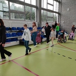 Uczniowie idą jeden za drugim przez salę gimnastyczną