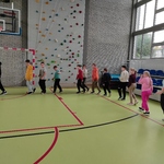 Grupa uczniów na sali gimnastycznej idzie gęsiego