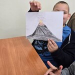 Uczeń pokazuje narysowany wulkan na kartce