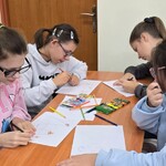Uczennice siedzą przy stole i rysują na kartkach