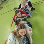 Dwie studentki i uczniowie siedzą na podłodze jeden za drugim