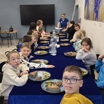 Grupa uczniów i nauczycielki siedzą wokół stołu w barze