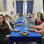 Grupa uczniów i nauczycielki siedzą wokół stołu w barze