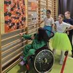Uczniowie stoją przy plakacie powieszonym na drabinkach