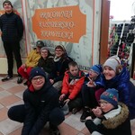 Grupa uczniów przed witryną zakładu krawieckiego.