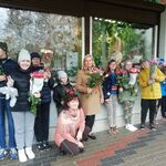 Uczniowie z opiekunami i panią florystką trzymają bukiety róż