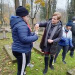 Nauczycielka zapala znicz trzymany przez uczennicę w ręku.
