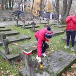 Uczeń stawia znicz na grobie nieznanego żołnierza. Uczennica stojąca przed grobem przygląda się koledze.
