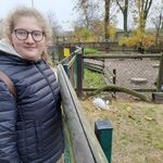 Dziewczyna  w okularach na tle wybiegu dla królików.