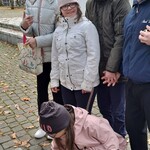 Uczniowie obserwują koleżankę stawiającą znicz na ziemi