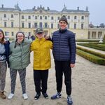 Czwórka uczniów stoi na alejce parkowej na tle Pałacu Branickich.