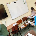 Uczniowie szukają obrazków pasujących do trzymanych w dłoniach.