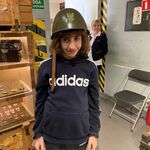 Uczeń w kasku żołnierskim stoi na tle wystawy muzealnej.