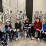 Grupa sześciu uczniów siedzi na tle kartonowej makiety -  żołnierzy.