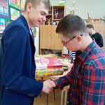 Dwóch chłopców stoi bokiem trzymając się za rękę.