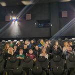 Grupa uczniów siedzi na kinowych fotelach.