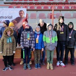 Grupa uczniów z nauczycielami na tle trybun stadionu.