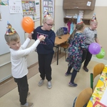 Grupa uczniów tańczy, w ręku trzymają balony.