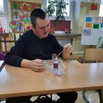 Uczeń siedzi przy stoliku. Przed nim stoi pojemnik z butelką z której wydobywa się piana.