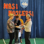 Pani Dyrektor wręcza List Gratulacyjny mamie laureata. Z tyłu stoi uczeń z wychowawczynią,