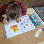 Uczennica siedzi przy stole pochylona nad otwartymi ćwiczeniami.