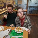 Dwóch uczniów siedzi przy stoliku. Przed nimi na talerzykach leżą gofry.