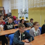Uczestnicy konkursu siedzą przy stolikach.
