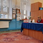 Uczeń czyta z kartki trzymanej w rękach. Jury konkursu siedzi za stołem przykrytym niebieskim obrusem.