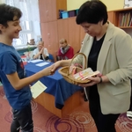 Pani prowadząca konkurs wręcza nagrodę uczestnikowi.