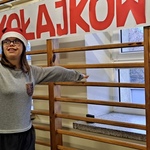 Uczennica w czapce mikołaja na tle drabinek i napisu Mikołajkowy bieg.