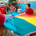 Przebrani uczniowie i nauczyciele bawią się chustą animacyjną i piłeczkami
