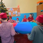  Przebrani uczniowie i nauczyciele bawią się chustą animacyjną i piłeczkami