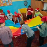 Przebrani uczniowie i nauczyciele bawią się chustą animacyjną i piłeczkami