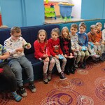 Grupa dzieci siedzi na kanapie w świetlicy.