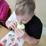 Uczeń siedzi przy stoliku i je kanapkę.