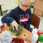 Uczennica kładzie bombkę na bazę w stroiku.