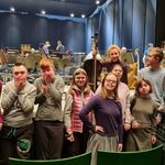 Grupa uczniów na tle instrumentów w operze.