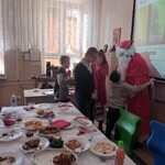 Wigilijny stół Obok Mikołaj i czwórka uczniów.