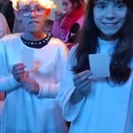 Dwie uczennice w strojach aniołów z opłatkiem w dłoniach.