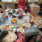 Troje dzieci przy świątecznym stole pani pomaga przy posiłku.