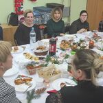 Grupa osób siedzi wokół  świątecznego stołu.